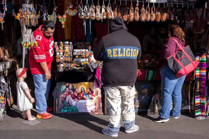 Street photographer captures humor and chaos in everyday life at a vibrant outdoor market scene with diverse shoppers.