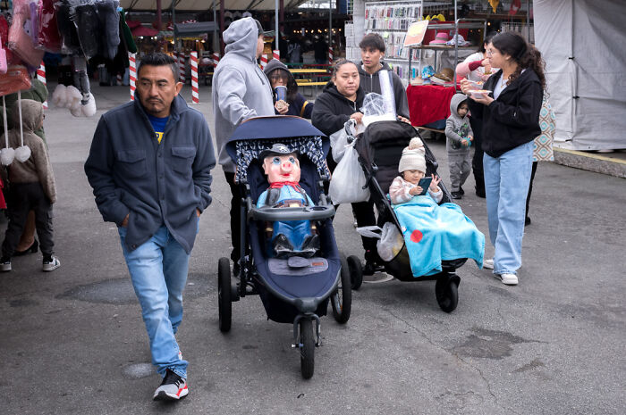 Street photographer captures humor and chaos in everyday life with people and unusual stroller scenes at a busy outdoor market.