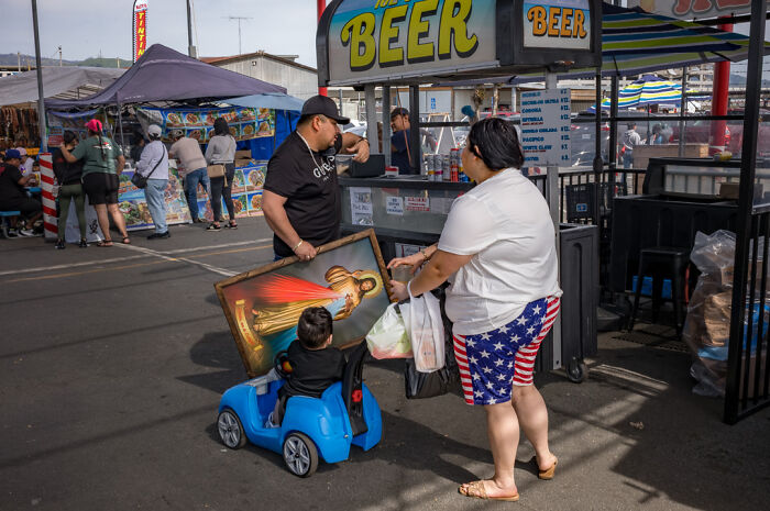 Street photographer captures humor and chaos in everyday life with candid scene at outdoor market featuring family and vibrant details.