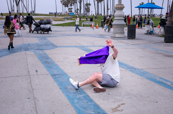 Man in casual clothes falling on pavement, captured by street photographer highlighting humor and chaos in everyday life.