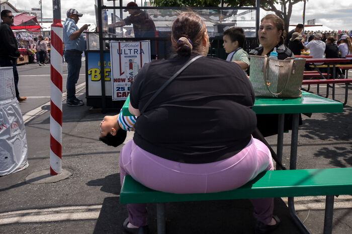 Street photographer captures humor and chaos in everyday life with candid shot of people at a busy outdoor event.