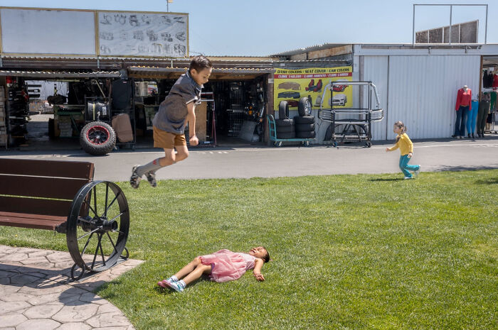 Children playing energetically in a street scene capturing the humor and chaos of everyday life by a street photographer.