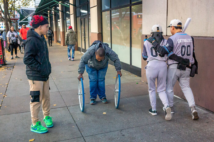 Street photographer captures humor and chaos of everyday life with candid shots on a busy urban sidewalk.