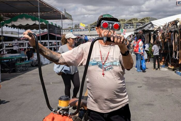 Man with vintage bicycle and humorous goggles, capturing the chaos of everyday life in street photography.