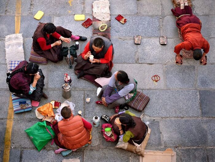 Group of people sitting and praying on stone pavement captured through Harjanto Sumawan’s candid photos.
