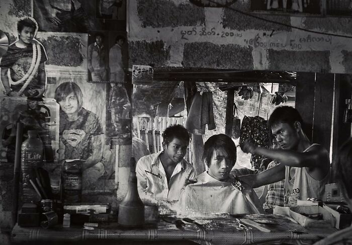 Black and white candid photo of a barber cutting hair, capturing life’s beauty through Harjanto Sumawan’s lens.