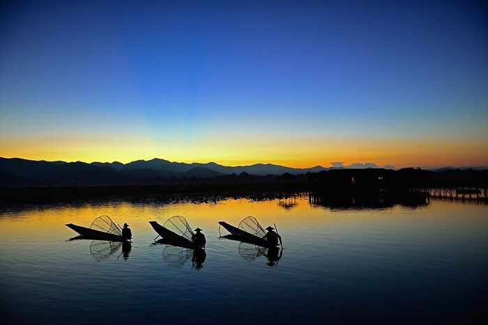Candid photo of fishermen on calm water at sunset, capturing life’s beauty through Harjanto Sumawan’s lens.