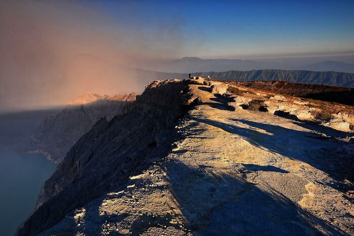 Mountain ridge at sunrise with long shadows and panoramic views, showcasing nature’s beauty through candid photography.