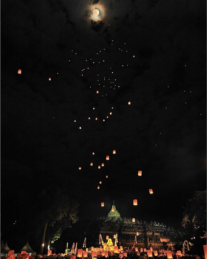 Lanterns rising into the night sky above an ancient temple, capturing life’s beauty through candid photography.