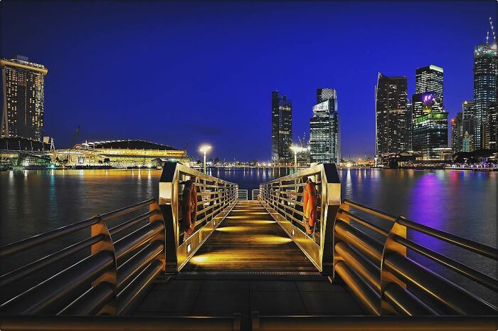 Night cityscape with illuminated pier and skyscrapers, showcasing candid photos that capture life’s beauty through a unique lens.