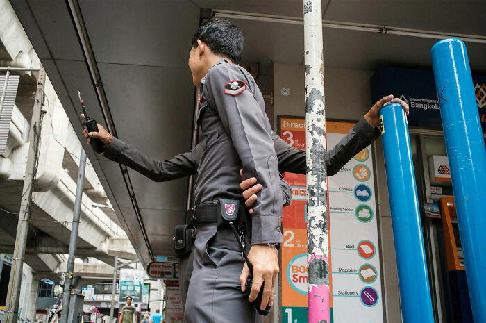 Police officer with multiple arms illusion created by street coincidence in urban setting, showcasing witty street coincidences.