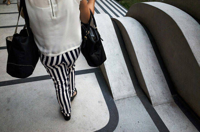 Person wearing striped pants walking on curved street pavement with matching patterns in street coincidences photo.