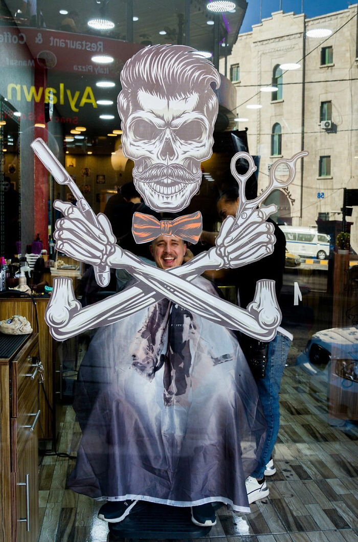 Man at barbershop with skeleton decal on glass creating a witty street coincidence in urban setting.