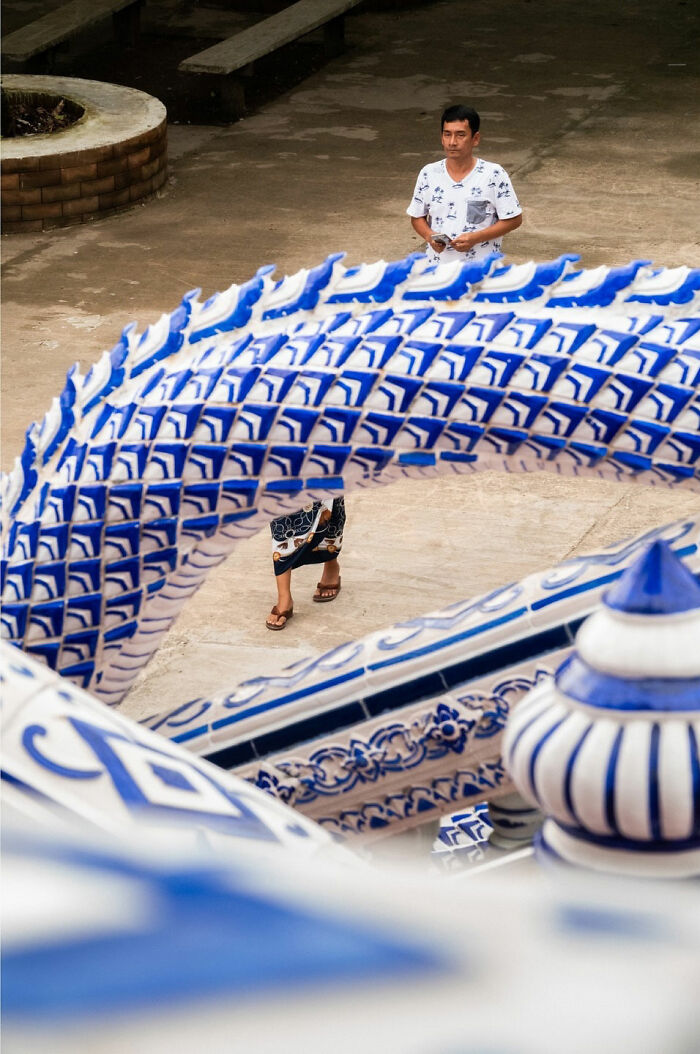 Man walking behind blue and white patterned street architecture in a captivating street coincidences photo.