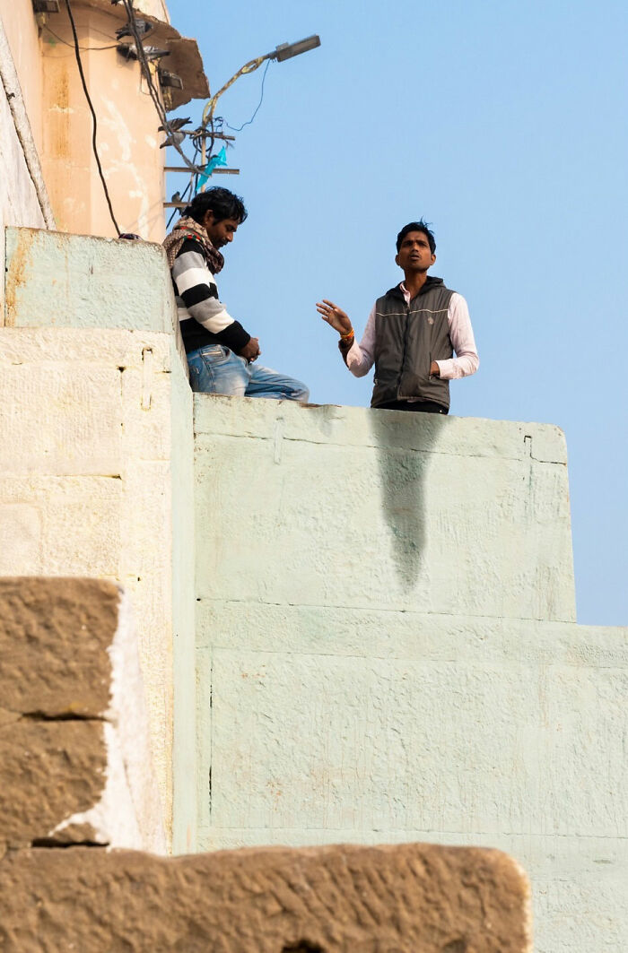 Two men talking on a rooftop, capturing a captivating and witty street coincidence moment in natural light.