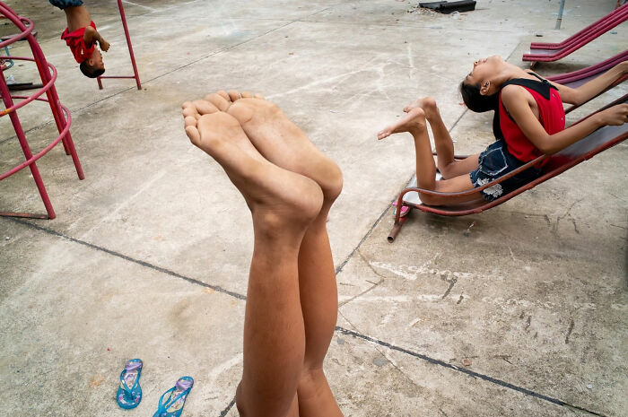 Children playing on swings and hanging upside down, showcasing captivating and witty street coincidences in an outdoor playground.