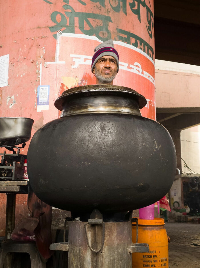 Man's head appearing inside a large pot, a witty street coincidence captured by Tavepong Pratoomwong.