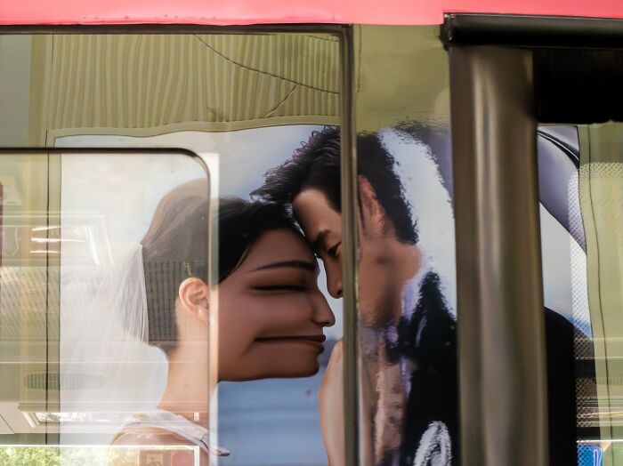 Street coincidences creating a humorous distorted image of a couple's faces touching through a bus window reflection.