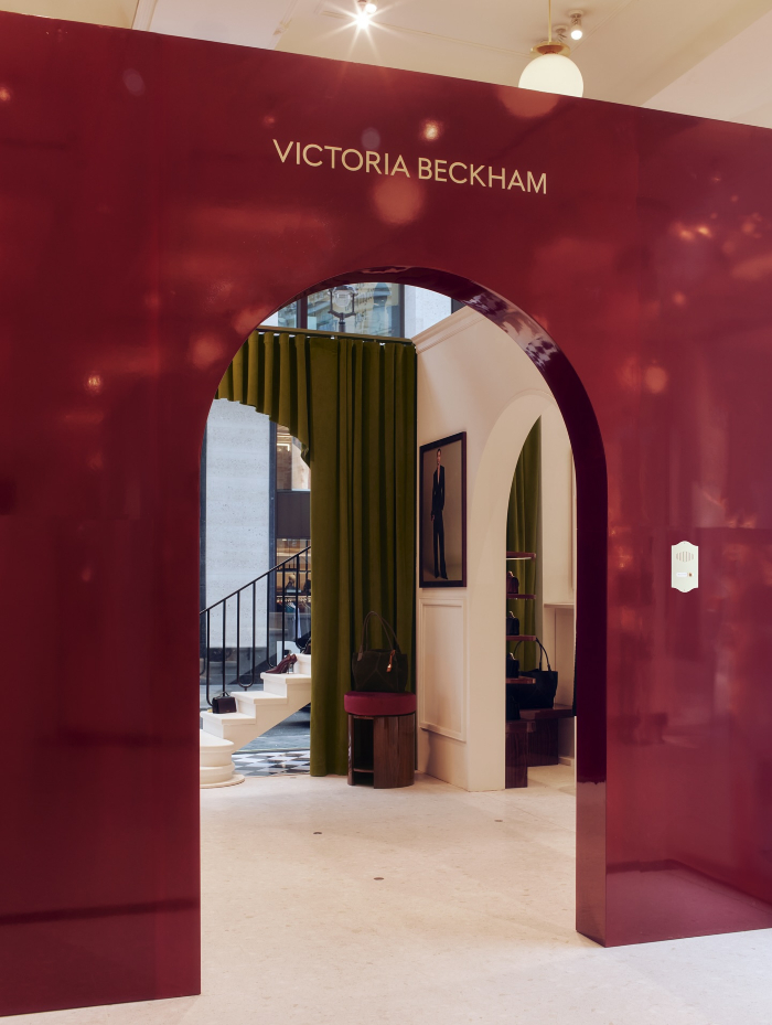 Victoria Beckham boutique interior with maroon archway and green curtains in a stylish modern retail space.