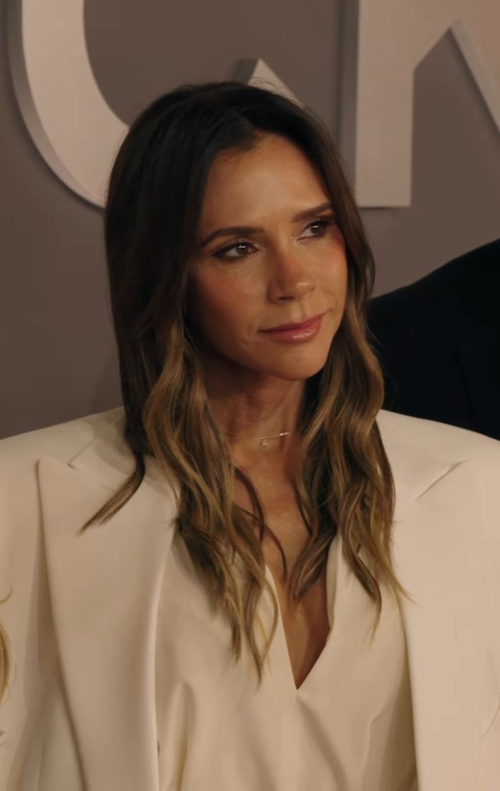 Victoria Beckham wearing a white blazer, looking thoughtful while discussing why she ditched her breast implants after Spice Girls era.
