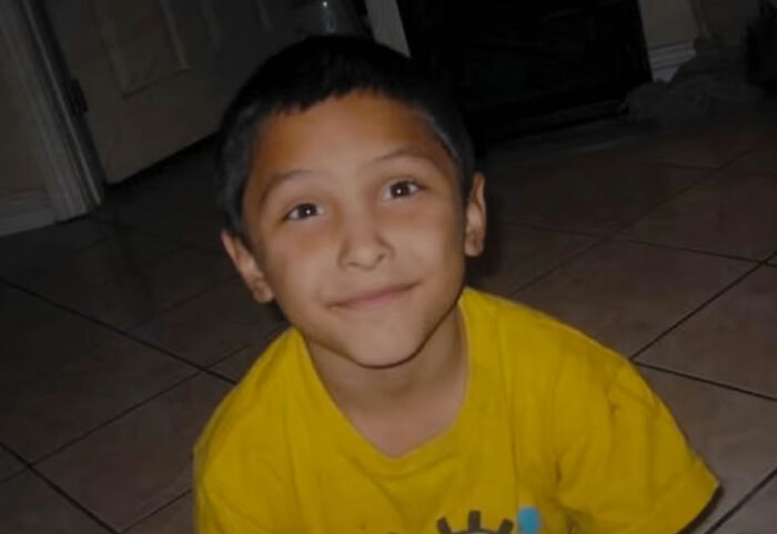 Young boy sitting on tiled floor, smiling at camera, representing true crime fans with confident expressions.