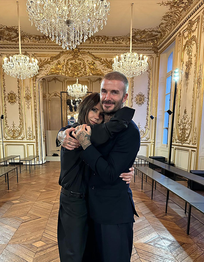 Victoria Beckham and David Beckham embracing in a luxurious room with chandeliers, highlighting Victoria Beckham breast implants.