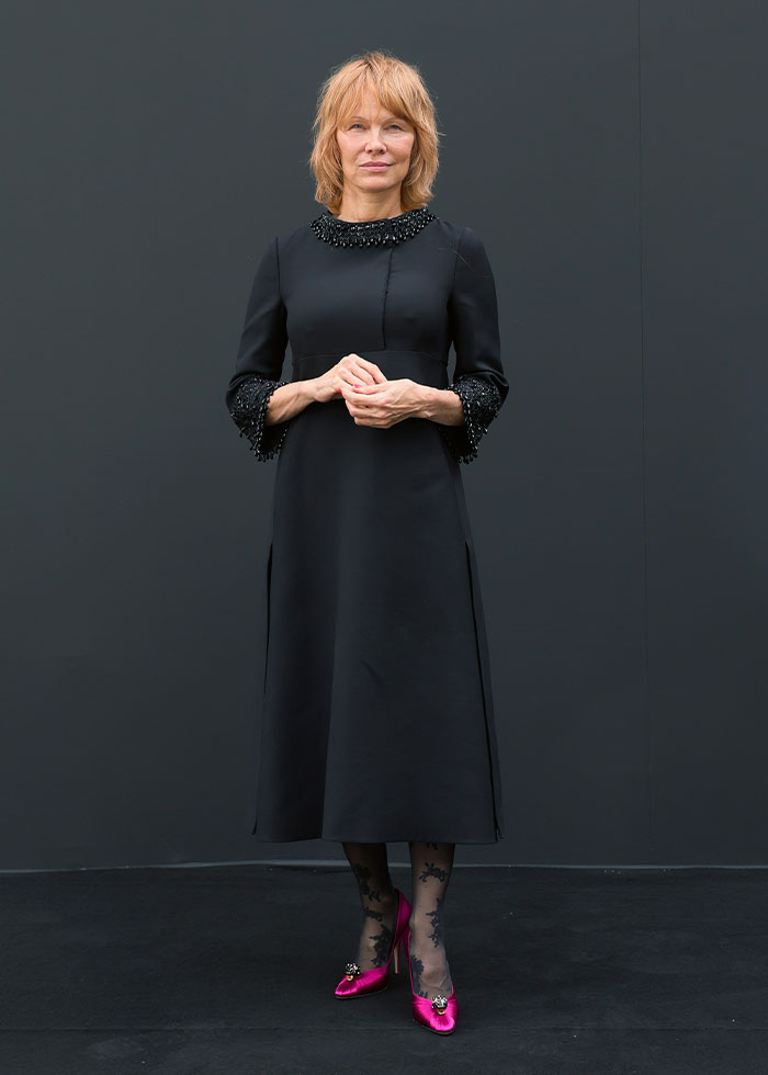 Woman in a black dress with embellished cuffs and collar paired with pink heels at Paris Fashion Week 2025 celebrity looks.