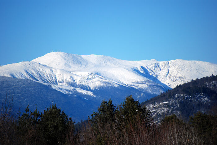 Snow-covered mountain under clear blue sky, showcasing incredible weather records and the power of our planet.