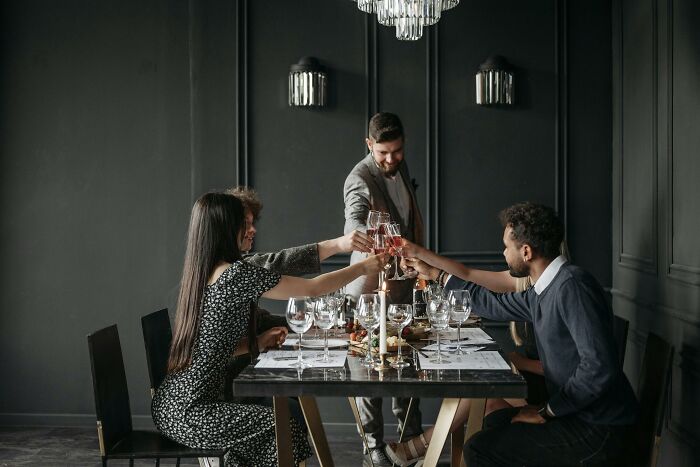 Group of friends toasting glasses around a table while casting votes on a creepy Halloween-inspired poll.