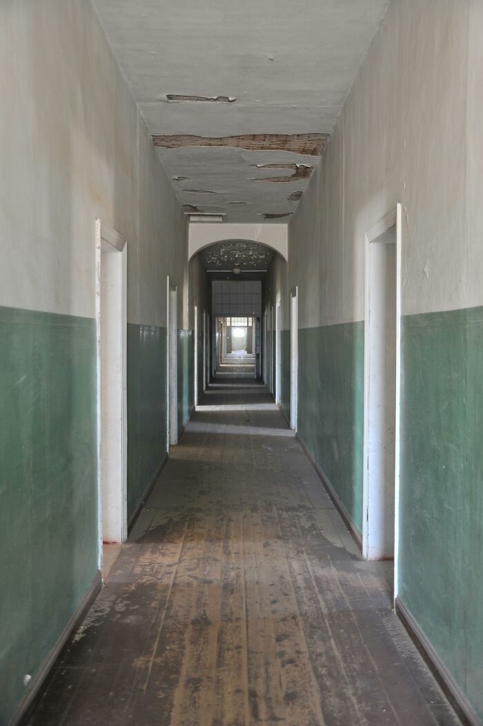 Creepy abandoned hallway with peeling paint and open doors, evoking a spooky Halloween-inspired vibe for poll voting.