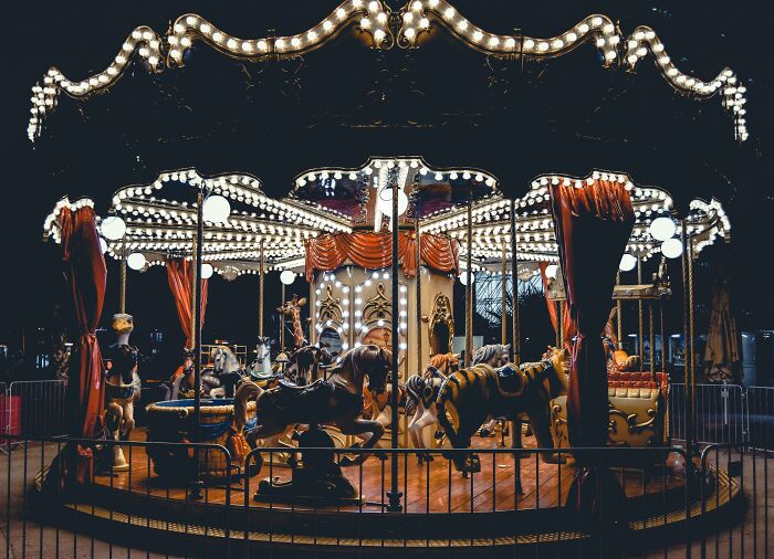 Vintage carousel lit up at night with animals and Halloween-themed decorations for a creepy Halloween-inspired poll.