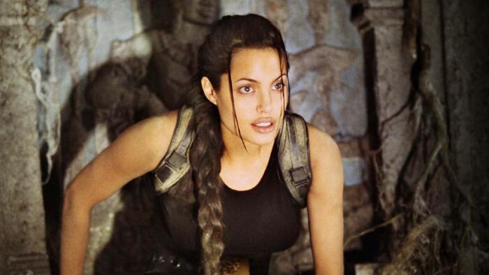 Woman with braided hair and tactical gear exploring a dark, ancient ruin illustrating unrealistic women movie tropes.