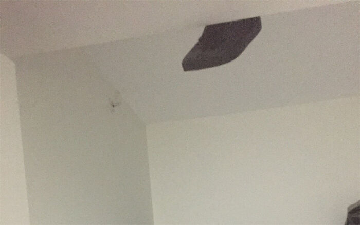 Patch on ceiling with a hole in a plain white room, creating a creepy photo moment that catches the eye.