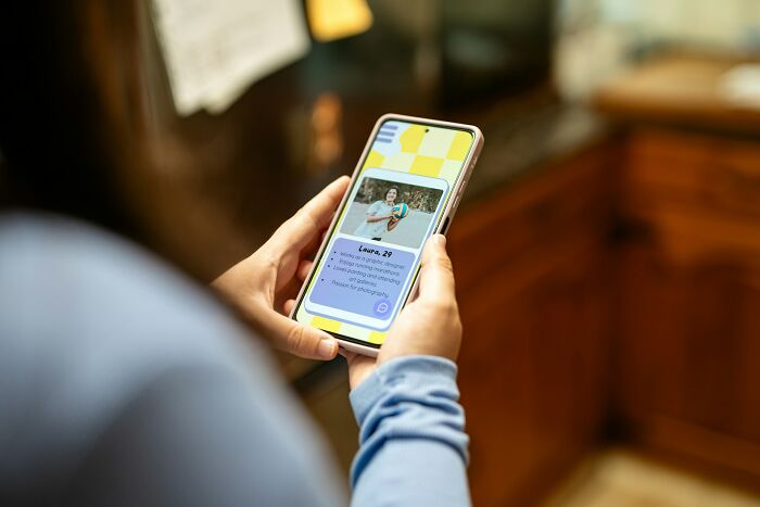 Person holding smartphone with an online dating profile visible, illustrating experience in online dating advice.