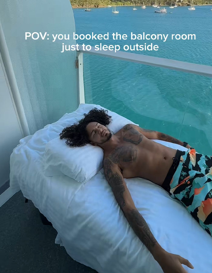 Man sleeping on a cruise balcony bed overlooking the ocean, highlighting viral video of strangers sleeping on cruise balconies.