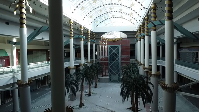 Empty ghost mall interior with palm trees and columns where urban explorers found a trapped dog needing rescue.