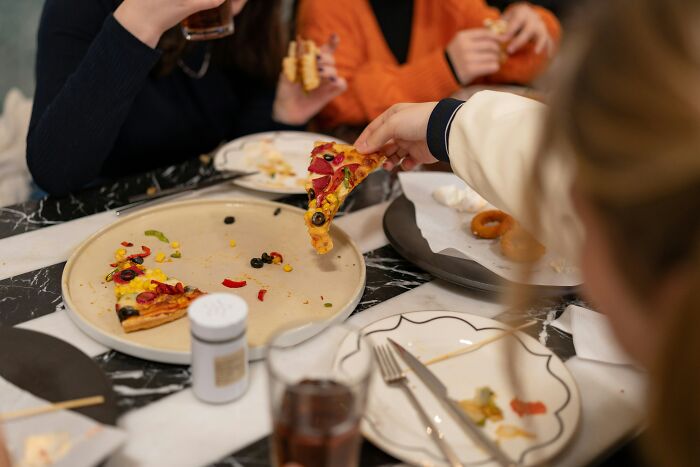 Children grabbing pizza slices at a table during a chaotic and memorable disastrous playdate parents wish to forget.