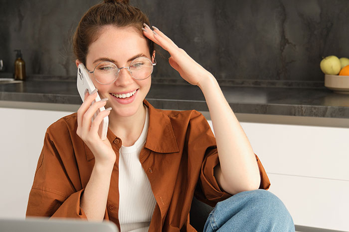 Young woman smiling and talking on phone during an ai scored job interview in real time from home. Young woman smiling and talking on phone during an ai scored job interview in real time from home.
