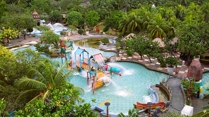 Water park with colorful slides and fountains surrounded by lush greenery, illustrating clueless dad swimming period idea scenario.