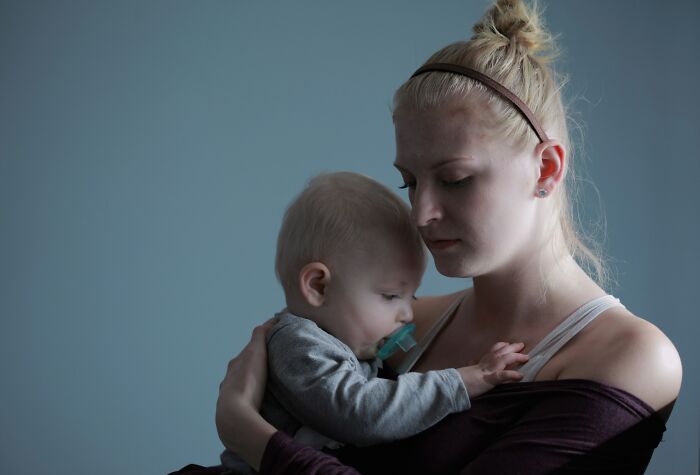 Worried wife holding baby, showing distress from emotional cruelty and feeling like she's going insane.