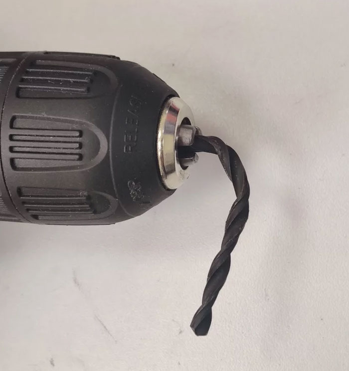 Close-up of a power drill with a bent drill bit showing a careless online shopping fail in tool purchase.