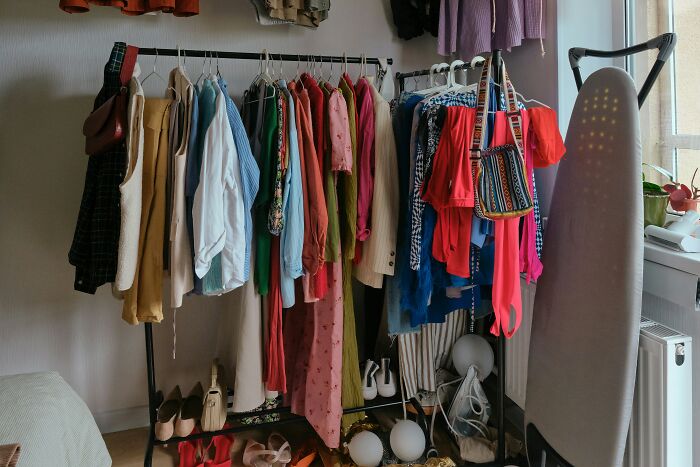 Cluttered room with colorful clothes on rack and shoes on floor, evoking chaotic scenes from disastrous playdates parents recall.