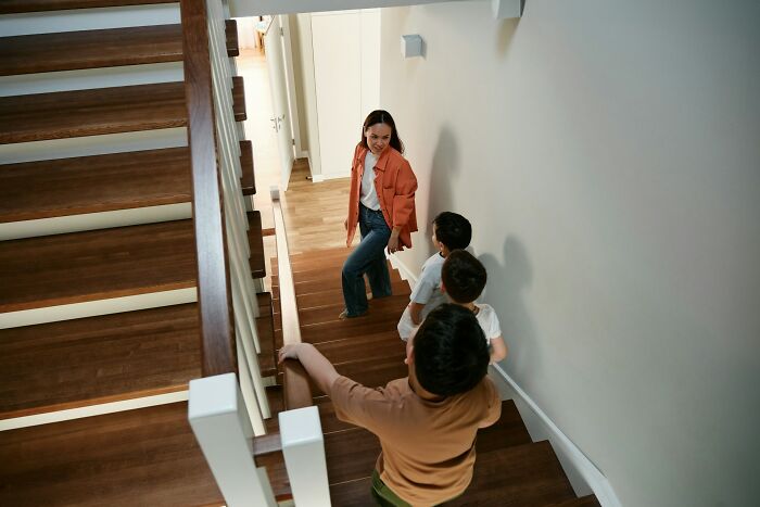 Mother cautiously watching three kids on wooden stairs during a chaotic playdate, illustrating disastrous playdates parents wish to forget.