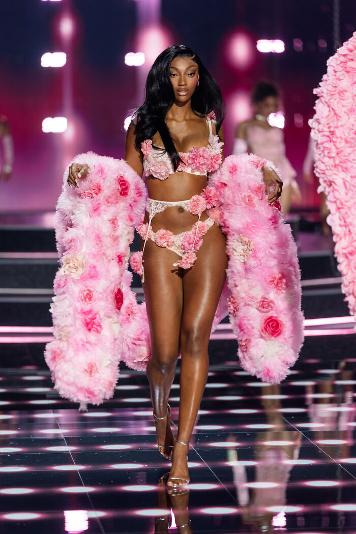 Model wearing floral lingerie and a pink feathered coat walking the runway at Victoria's Secret fashion show stunning runway looks.