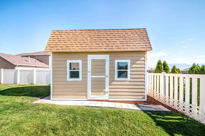 Small backyard house with beige siding and white trim, representing annexe son house and family relationship concept.
