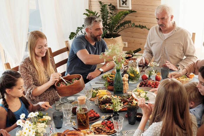 Family having a tense dinner with wife confronting brother-in-law over racist slurs while mother-in-law looks upset.