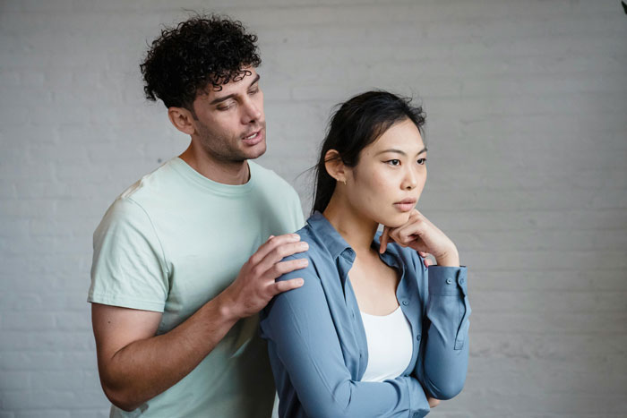 Wife visibly upset confronting brother-in-law about racist slurs during tense family dinner interaction indoors.