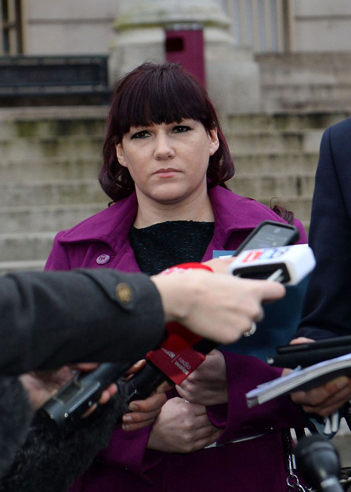 Woman in purple coat speaking to reporters outside courthouse about rock star fatally attacked in prison case.