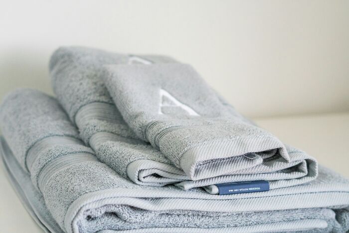 Stack of gray towels folded neatly on a white surface, symbolizing preparedness for messy or disastrous playdates parents face.