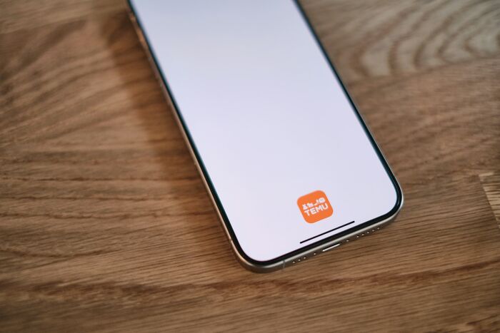 Smartphone displaying a brand logo on screen, placed on wooden surface, highlighting internet’s favorite game trends.